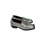Silver loafers with a strap on a white background