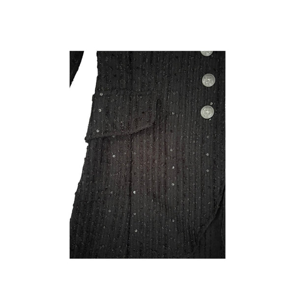 Close-up of a black textured garment with buttons on a white background