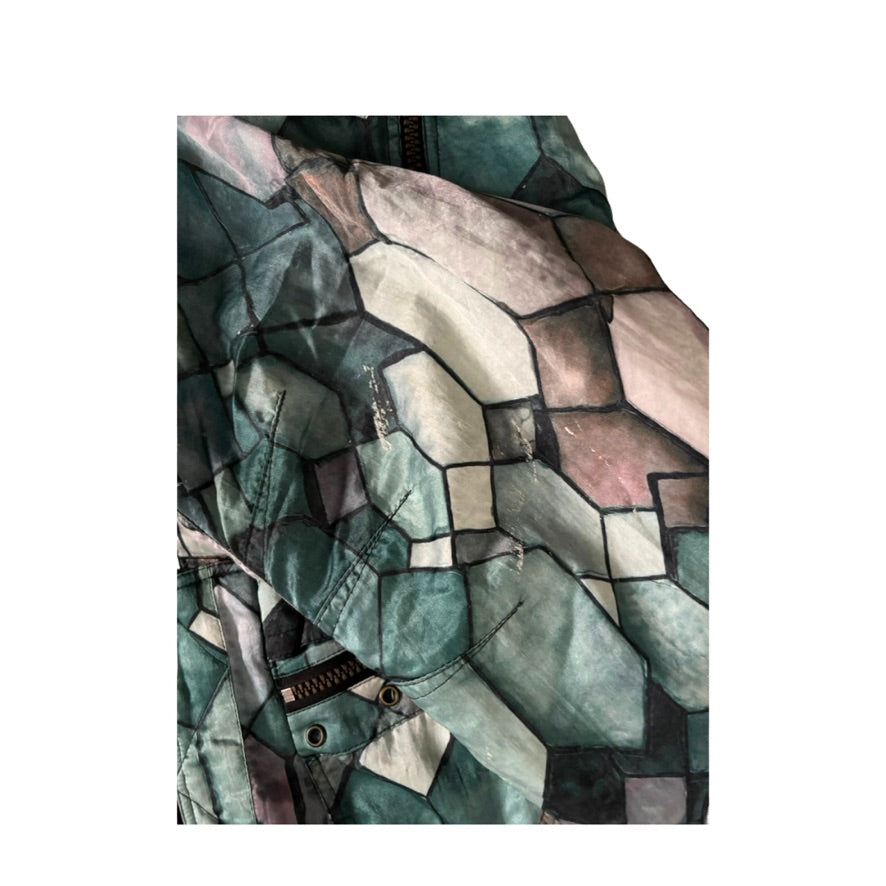 Close-up of a patterned fabric with geometric shapes in green, brown, and beige tones.