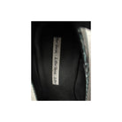 Close-up of a black shoe with a label on a white background