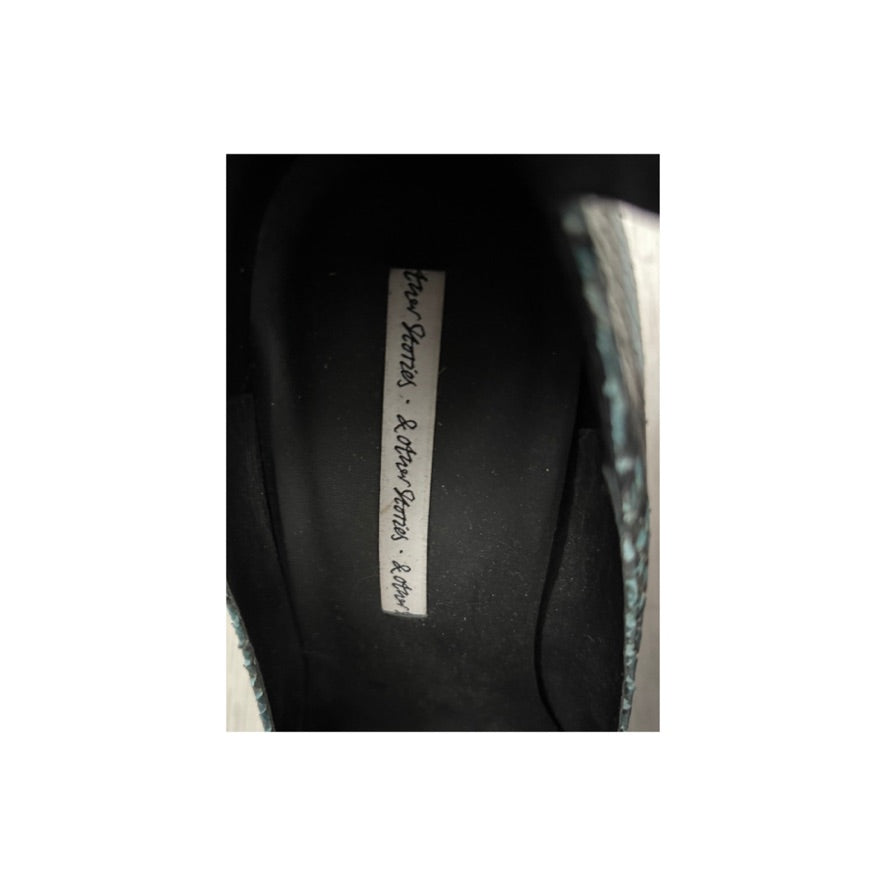 Close-up of a black shoe with a label on a white background