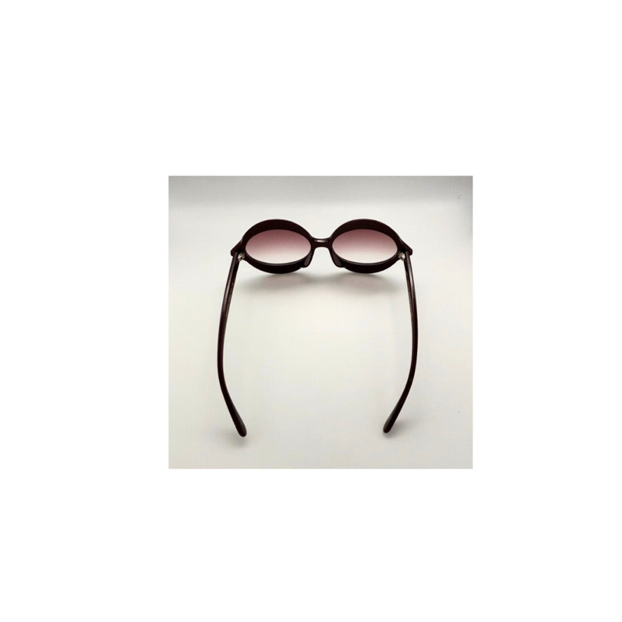 Sunglasses with black frame and pink-tinted lenses on a light gray background