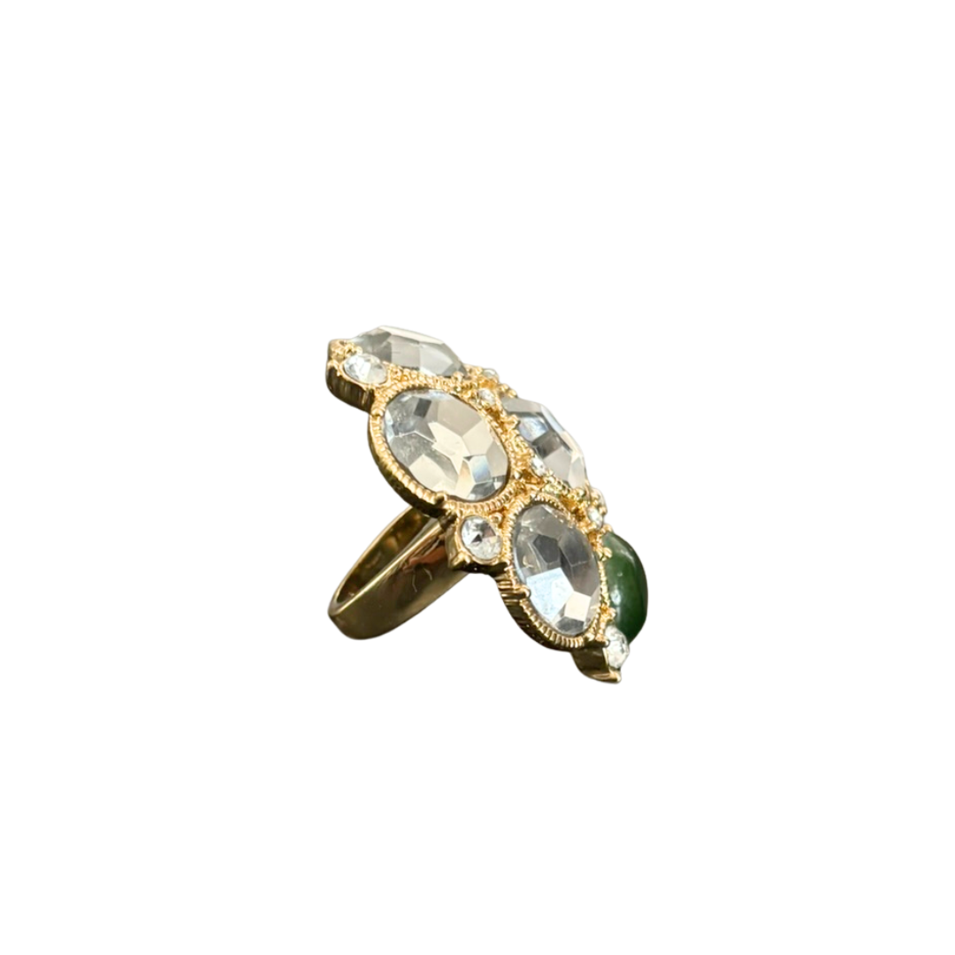 Gold ring with green and clear gemstones on a white background