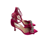 Fuchsia high-heeled shoes with decorative bow on a white background