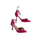 Pair of pink high-heeled shoes with bow details on a white background