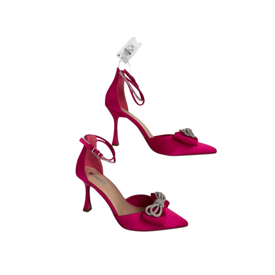 Pair of pink high-heeled shoes with bow details on a white background