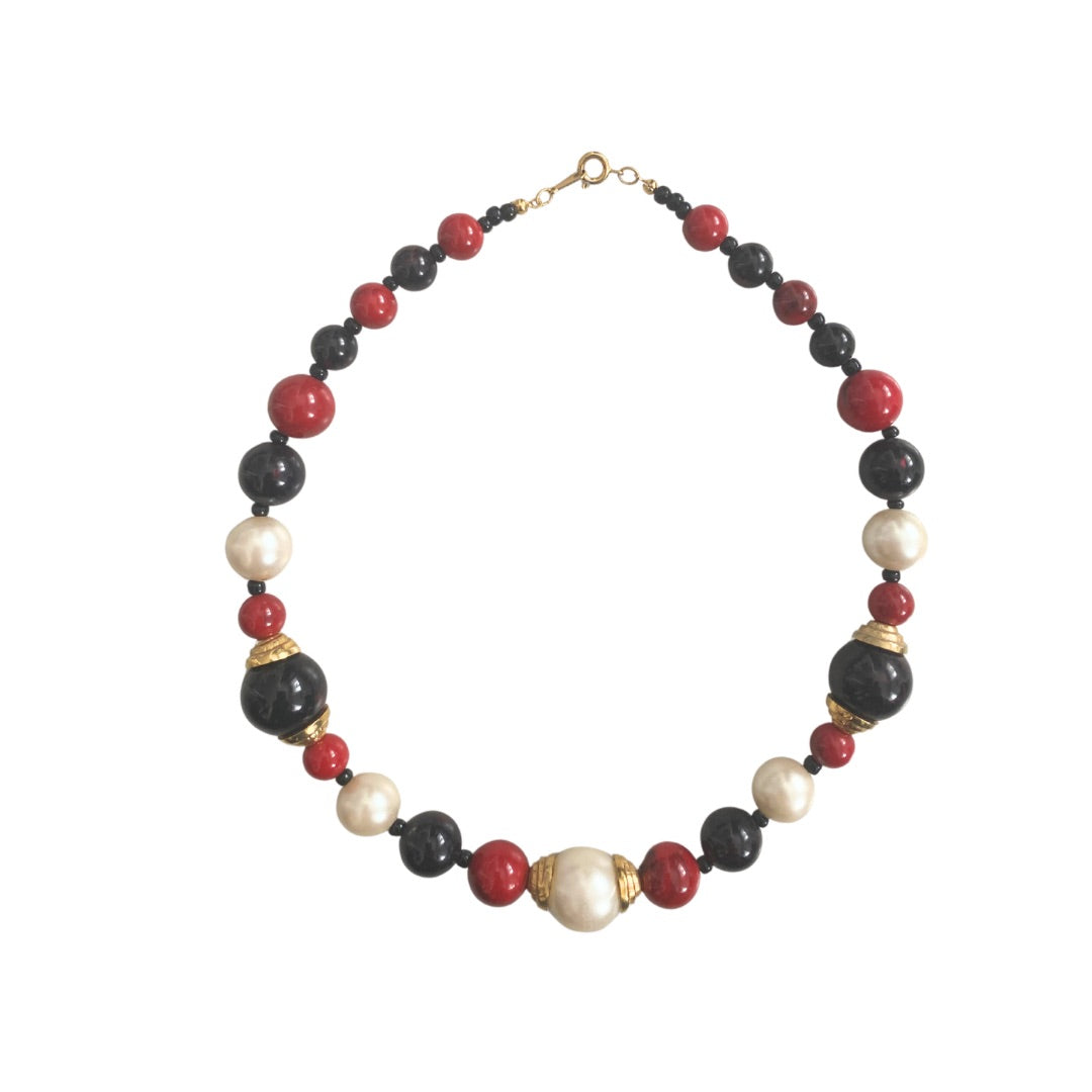 A vintage necklace featuring a combination of deep ruby red, onyx black, and soft ivory-hued faux pearls with gold-tone hardware.