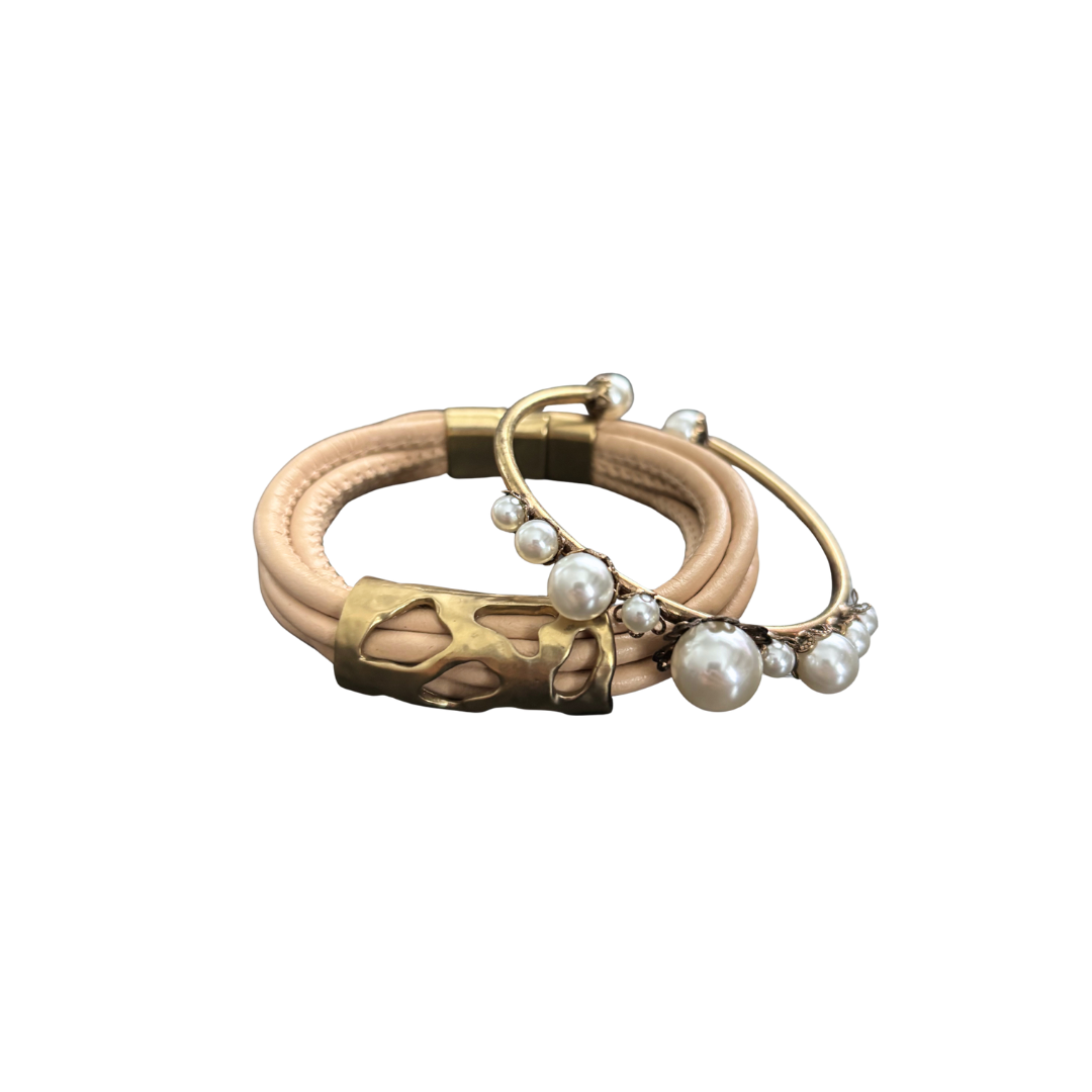 Bracelet and cuff with gold accents and pearl embellishments on a white background