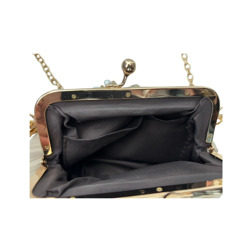 Close-up of a black handbag with gold frame and chain handle on a white background