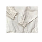 Close-up of a beige shirt with rolled-up sleeves on a white background
