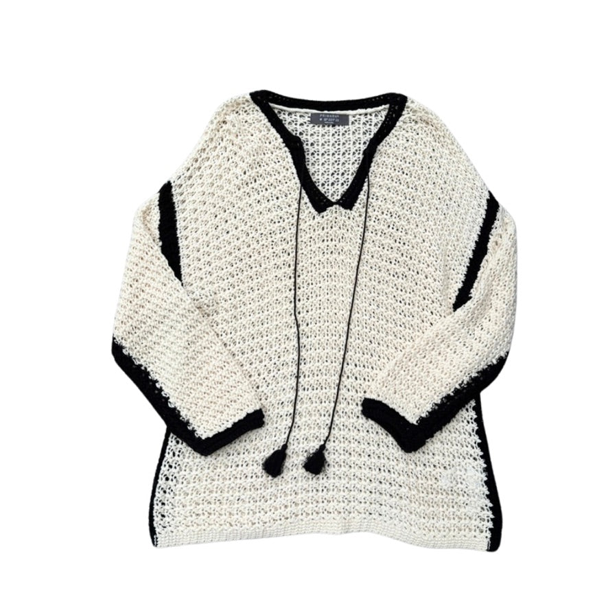 Cream crocheted sweater with black trim on a white background