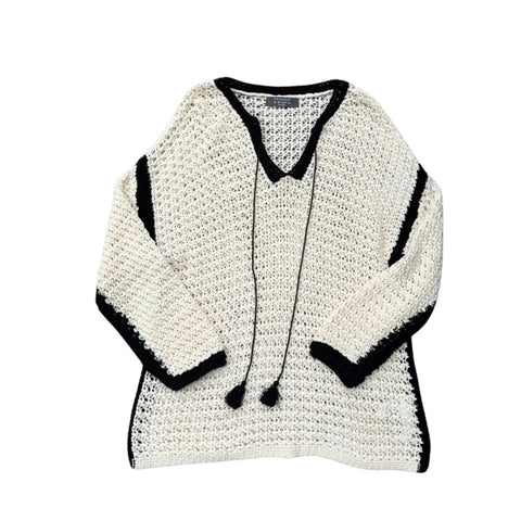 Cream crocheted sweater with black trim on a white background