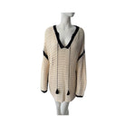 Beige and black crocheted sweater on a mannequin against a white background
