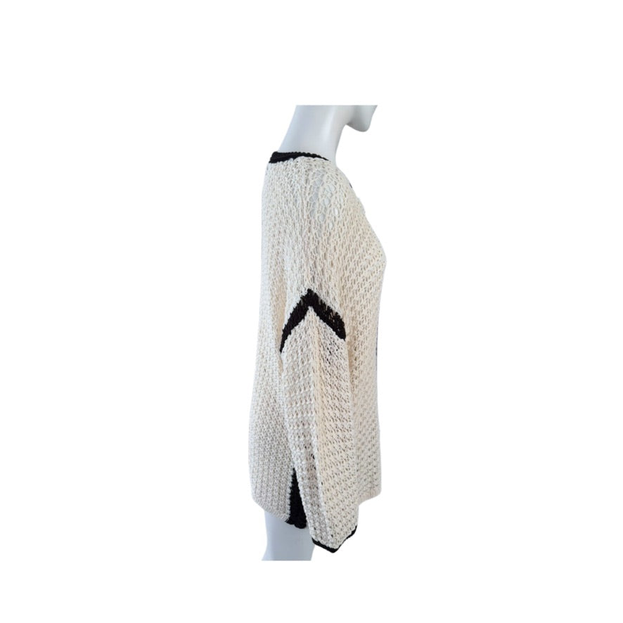White knitted poncho with black accents on a mannequin against a white background