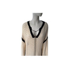 Mannequin wearing a beige cardigan with black trim on a white background