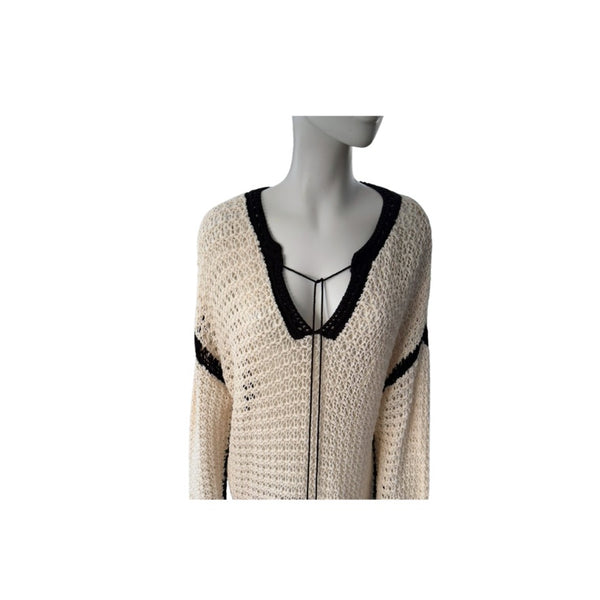 Mannequin wearing a beige cardigan with black trim on a white background