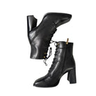 Pair of black leather boots with high heels on a white background
