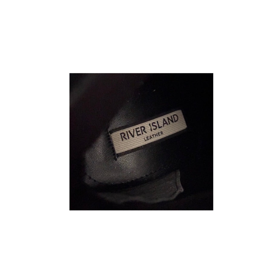 Close-up of a 'River Island Leather' label on a dark background