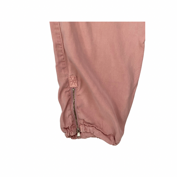 Close-up of a pink pants leg with a zipper on a white background