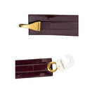 Two burgundy leather luggage tags with gold and silver hooks on a white background