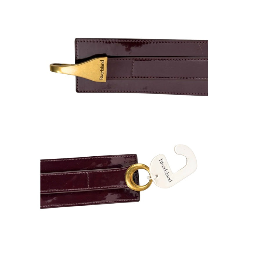 Two burgundy leather luggage tags with gold and silver hooks on a white background