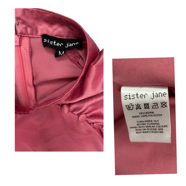 Pink garment with 'sister jane' label and care instructions on a white background