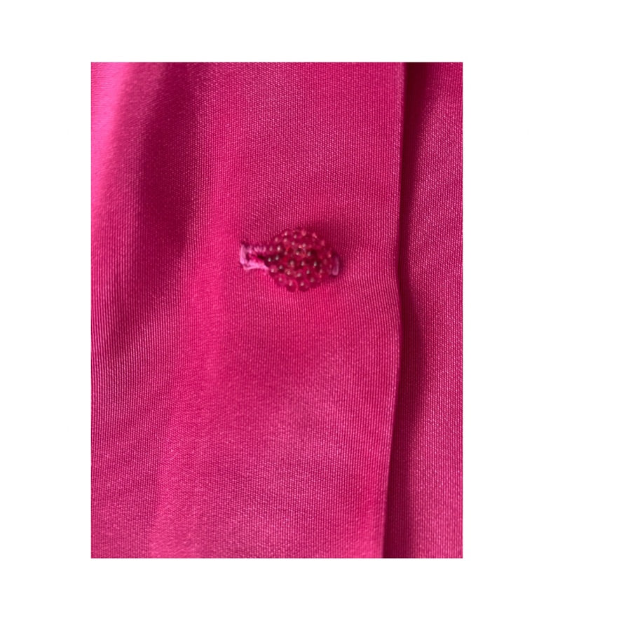 Close-up of a pink polo shirt with a small embroidered logo on a white background
