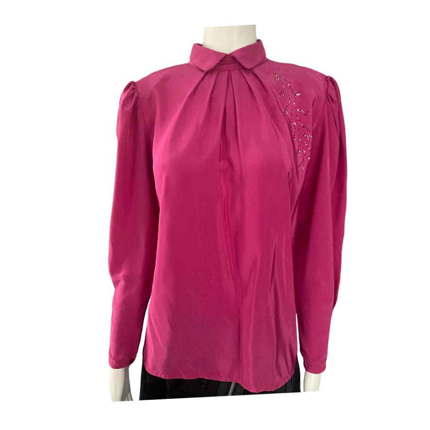 Pink blouse with decorative details on a mannequin against a white background