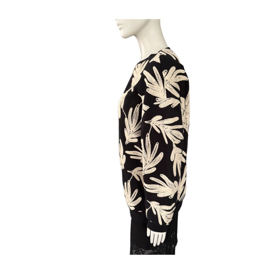 Black sweatshirt with beige leaf pattern on a mannequin against a white background