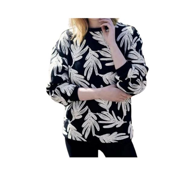 Black sweater with white leaf pattern worn by a person on a white background