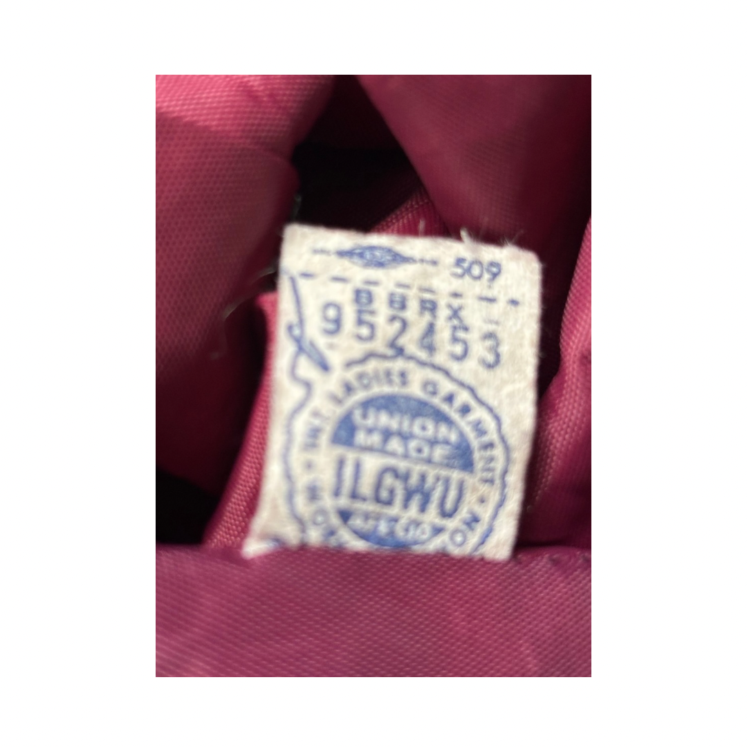 Label on a garment with 'ILGWU' and numbers, set against a red fabric background.