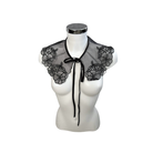 Black lace collar with floral designs on a mannequin bust against a white background