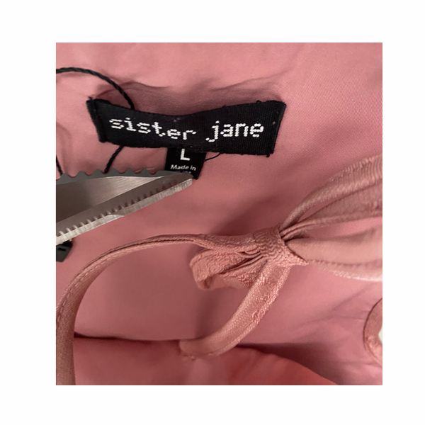 Pink garment with 'sister jane' label with visible scissors point