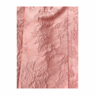 Pink textured fabric with floral patterns on a white background