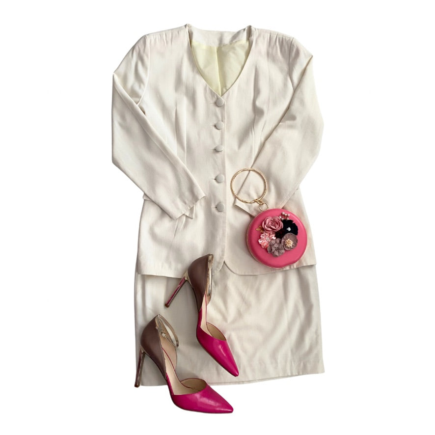 Cream outfit with pink shoes and a matching pink handbag on a white background