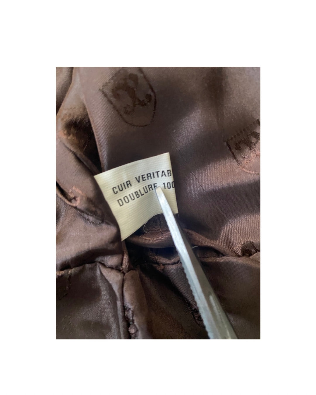 Close-up of a brown leather jacket with a label on a white background