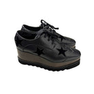 Black platform shoes with star designs on a white background