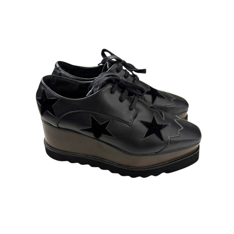 Black platform shoes with star designs on a white background
