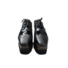 Black platform shoes with star cutouts on a white background