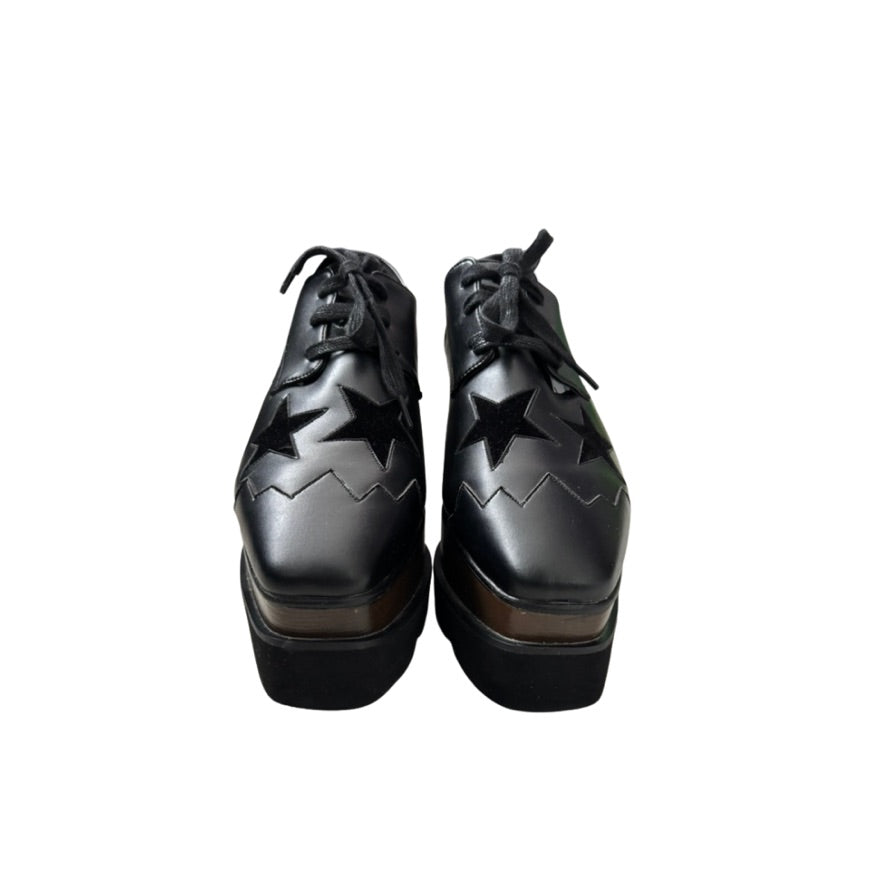 Black platform shoes with star cutouts on a white background