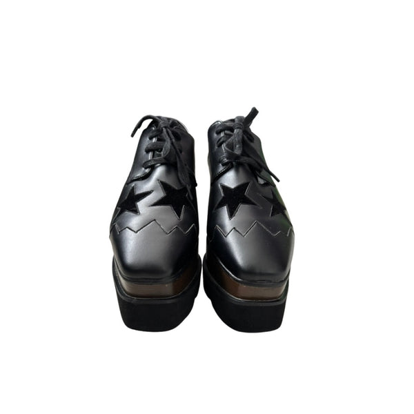 Black platform shoes with star cutouts on a white background