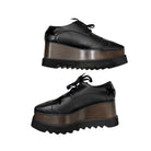 Black platform shoes with brown soles on a white background