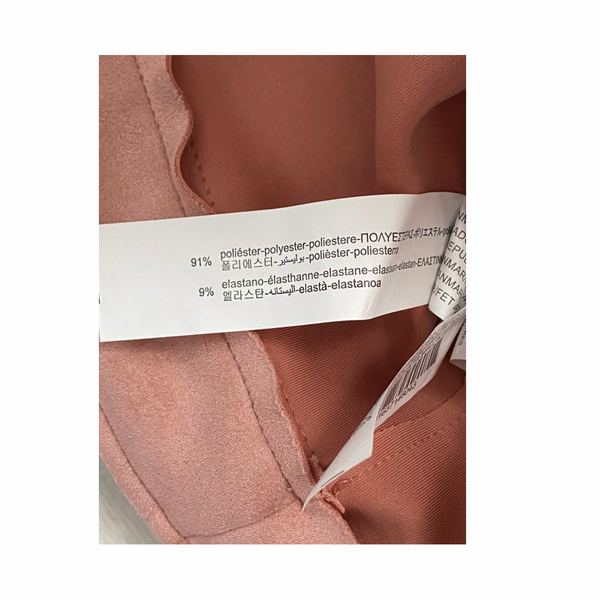 Close-up of a fabric label on a pink garment with text and percentages.