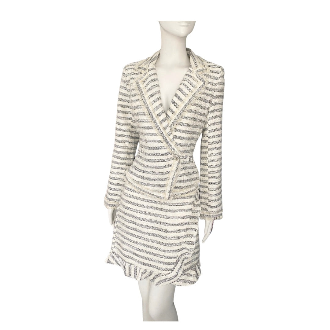 A cream colored tweed skirt suit with horizontal stripes, structured blazer and ruffle detailing, displayed on a mannequin.