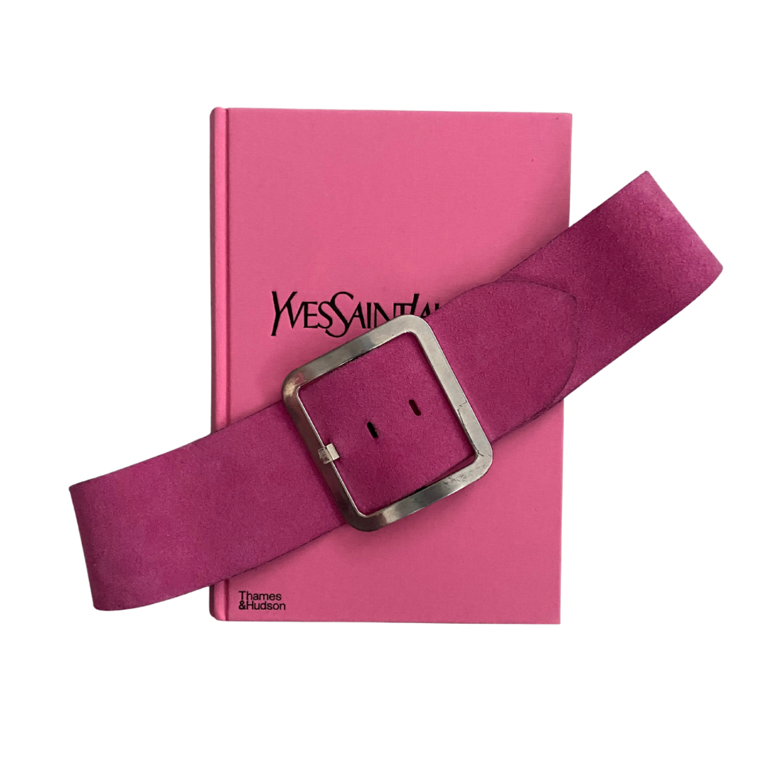 Pink belt with silver buckle on a pink book by Yves Saint Laurent
