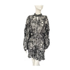 Sheer floral print mini dress with high neckline, button cuffs, and ruffled hem, displayed on a mannequin.