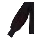 Black sweater sleeve with decorative cut-out pattern on a white background