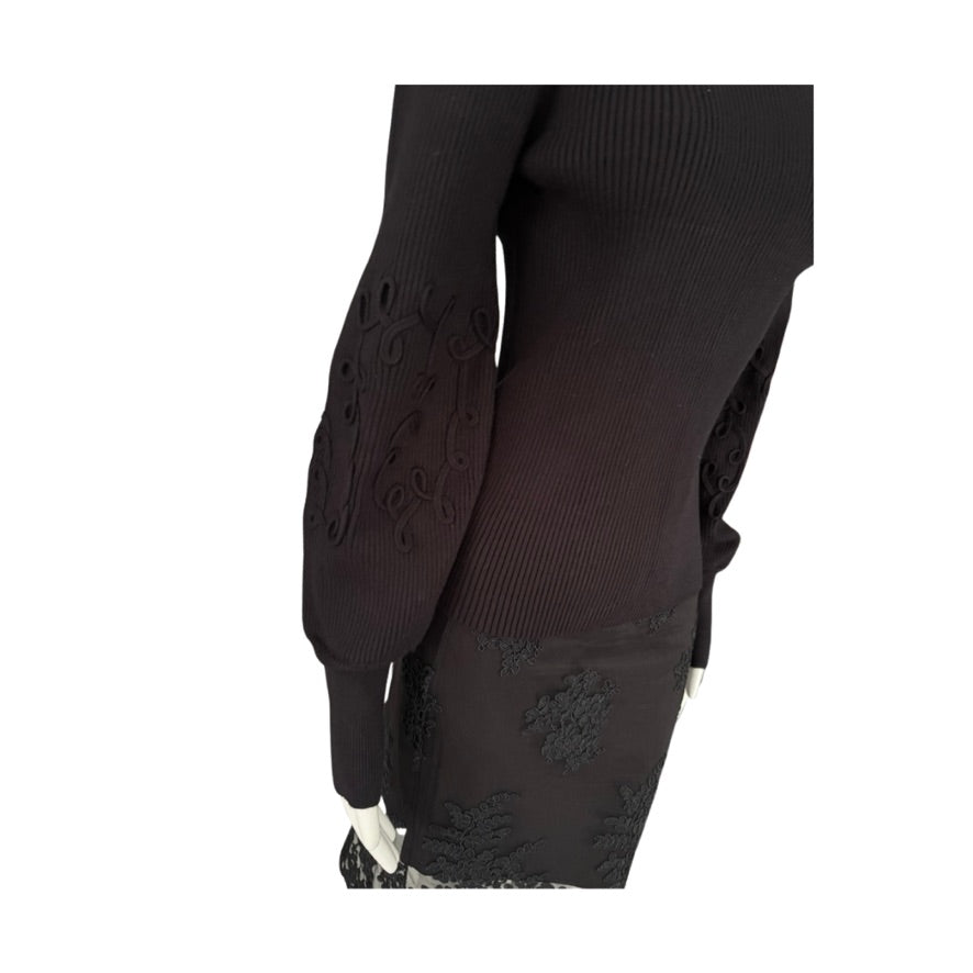 Black sweater with intricate lace detailing on a white background
