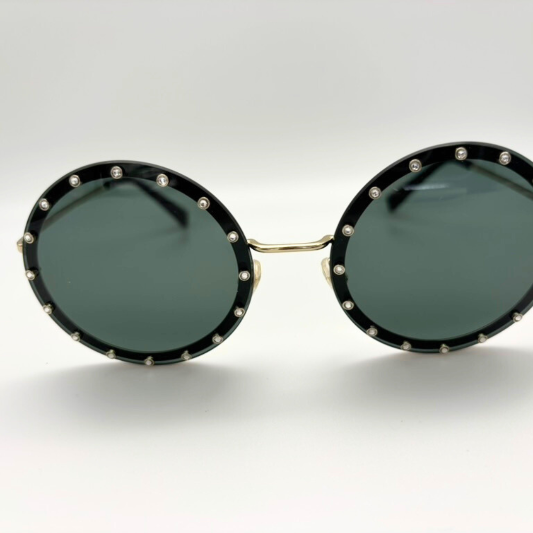 Round sunglasses with black frames and green lenses on a white background