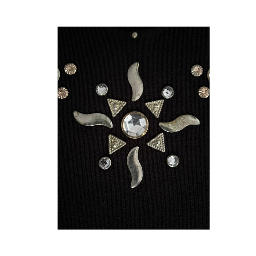 Decorative brooch with sun design and rhinestones on a black background
